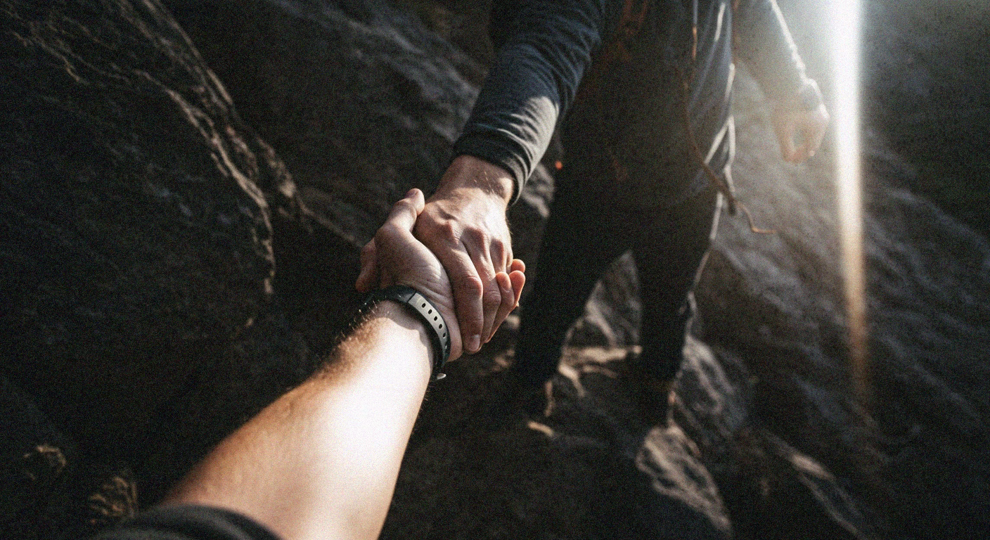 A person extends a helping hand, symbolizing support and morale, while hiking on rocky terrain. - heatseekerproject.com